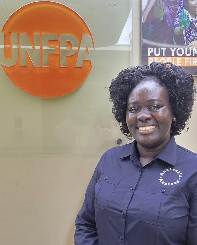 A woman standing in front of the UN Populations Fund sign (UNFPA).